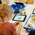 Child playing with building blocks and using a tablet device
