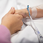 Photo of a nurse and patient holding hands.