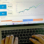 Hands on keyboard with a chart on a laptop screen.