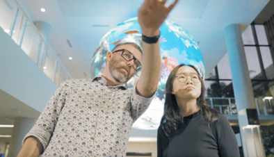 Photo of two researchers looking at a large digital media display.