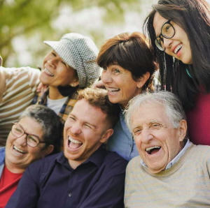 Five people of mixed ages seated together outside, facing the same direction and smiling for a photo