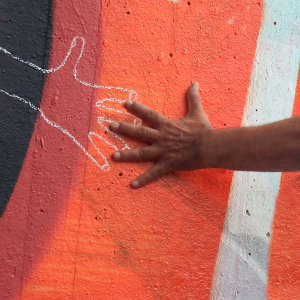 Hand reaching out to touch a chalk silhouette of a hand on a colourful background